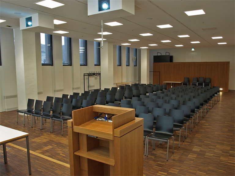 Aufnahme des Veranstaltungsraums Auditorium mit Blick auf Rednerpult, Beamer und Bestuhlung